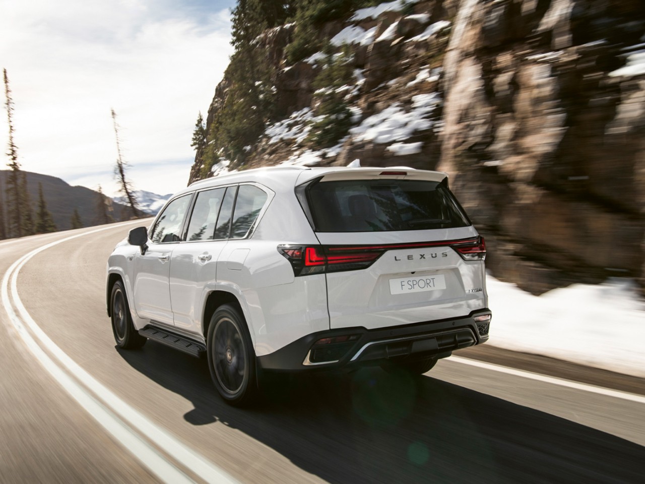 A white Lexus LX driving on a mountain road