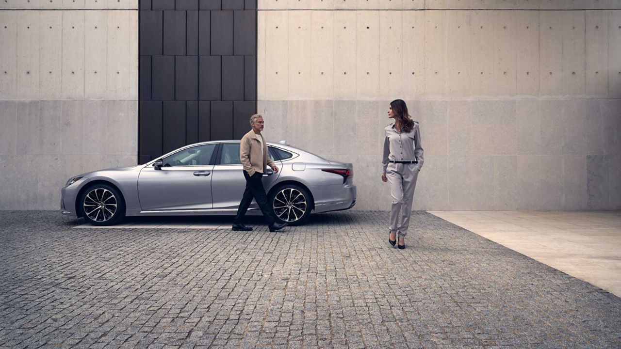 A man stood in the foreground of a Lexus LS