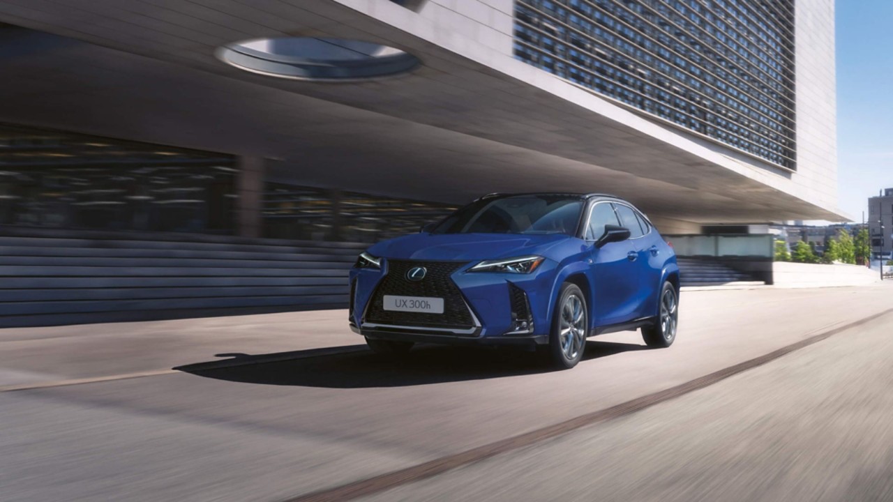 A blue Lexus UX driving in a city location