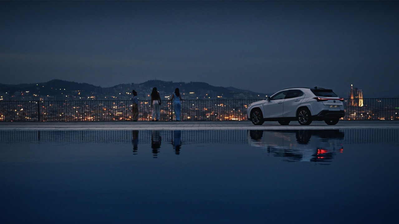 Three people stood next to a Lexus UX 