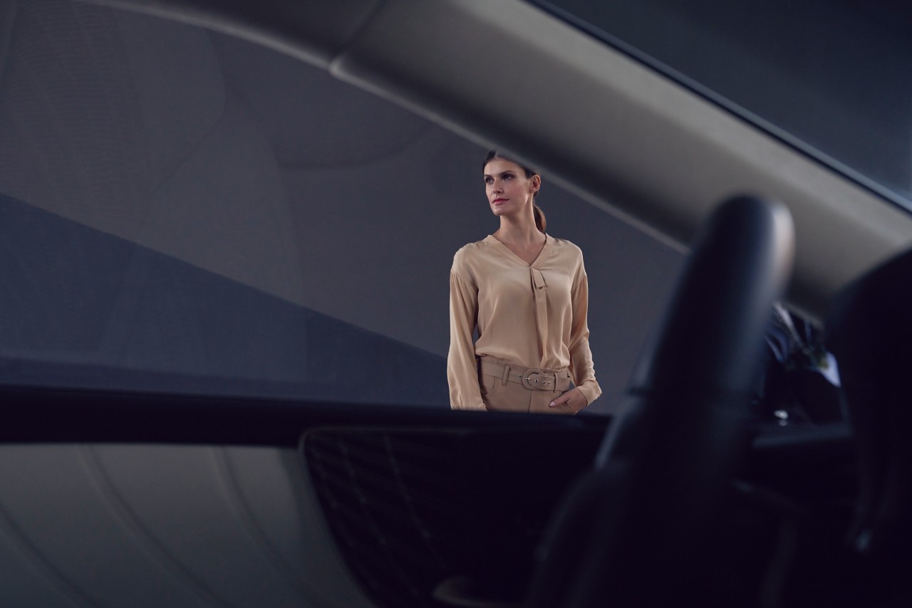 A woman standing within the background of a Lexus