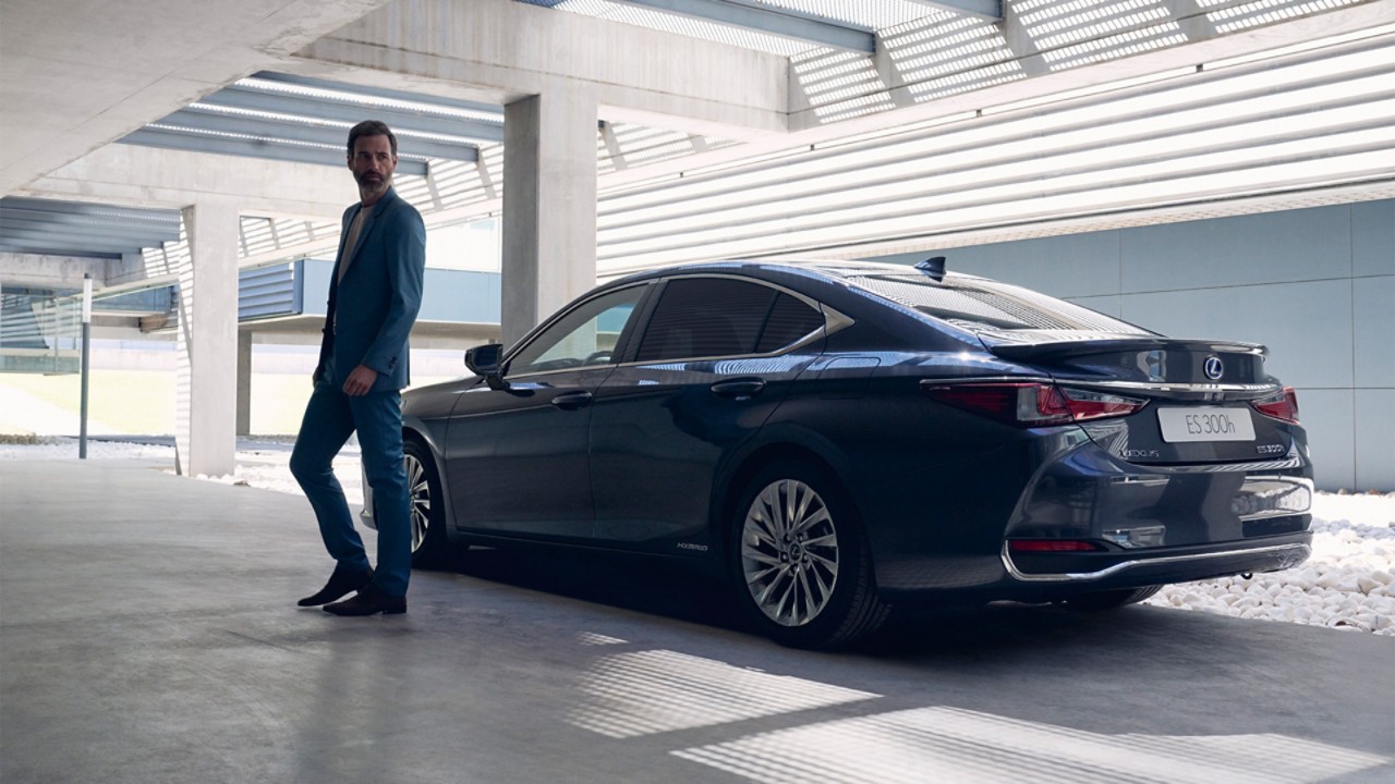 A person standing next to a Lexus