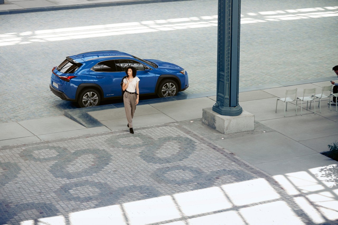 A woman walking away from a Lexus UX 300e 