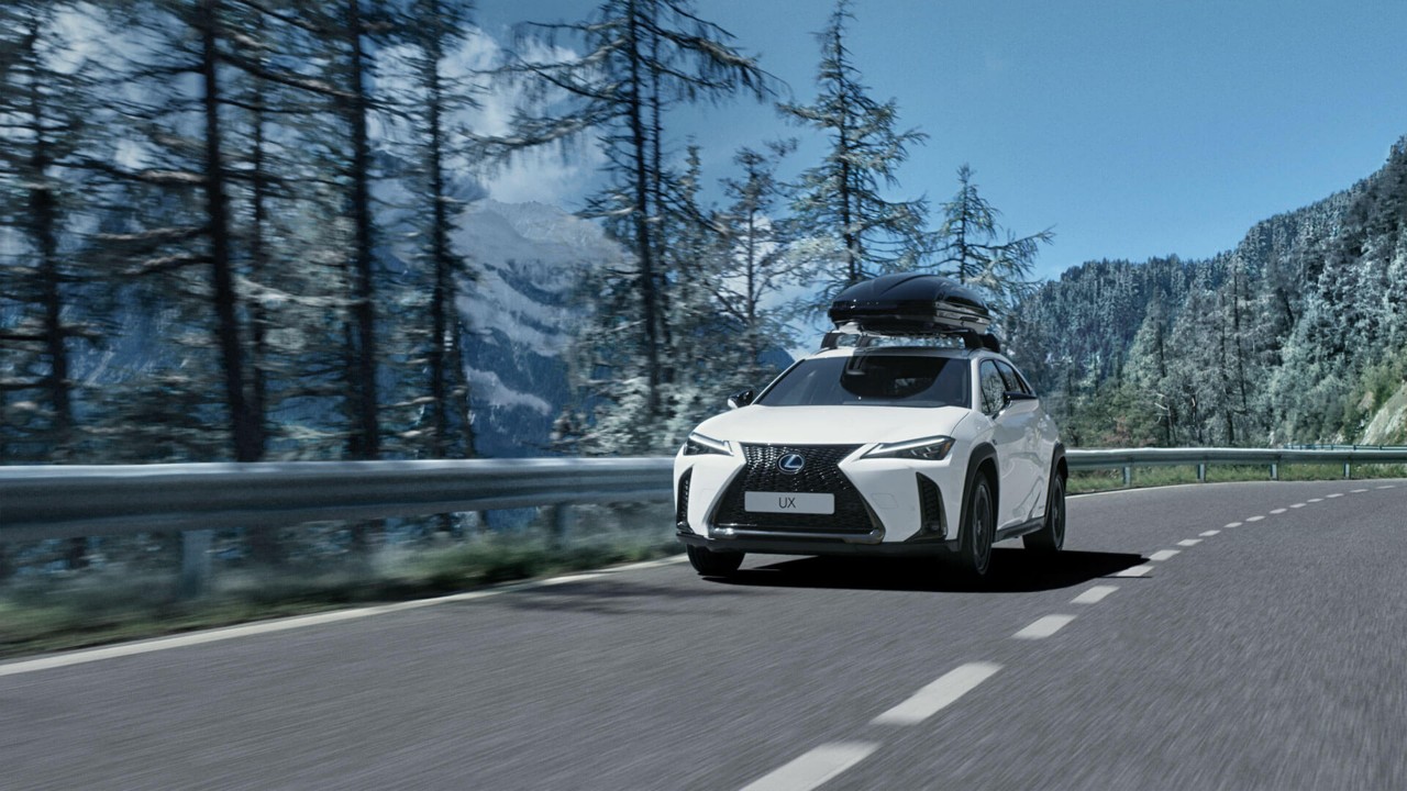 A Lexus UX with a roof box driving 