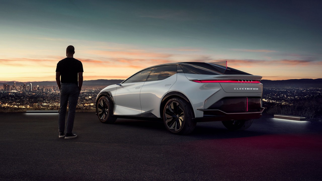 A man and Lexus LF-Z concept car looking over a city view 